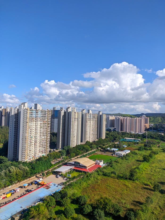 Aerial view of tall residential buildings in Pune, India, with lush greenery and a vibrant sky.